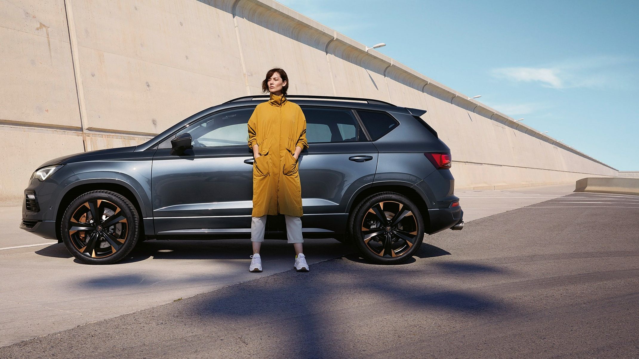 Ein CUPRA Ateca in grau, eine Frau steht davor.