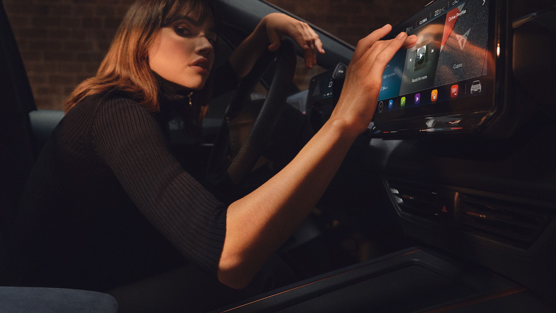 Eine Frau sitzt in einem CUPRA Born und bedient das Infotainment Display.