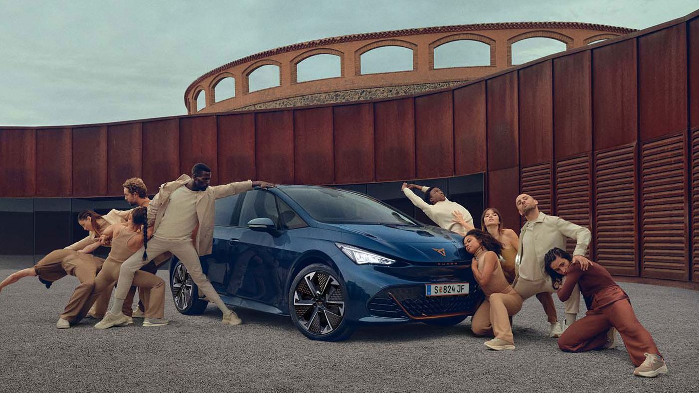 Ein blauer CUPRA Born steht auf einem Platz, mehrere Personen befinden sich links und rechts neben dem Fahrzeug.