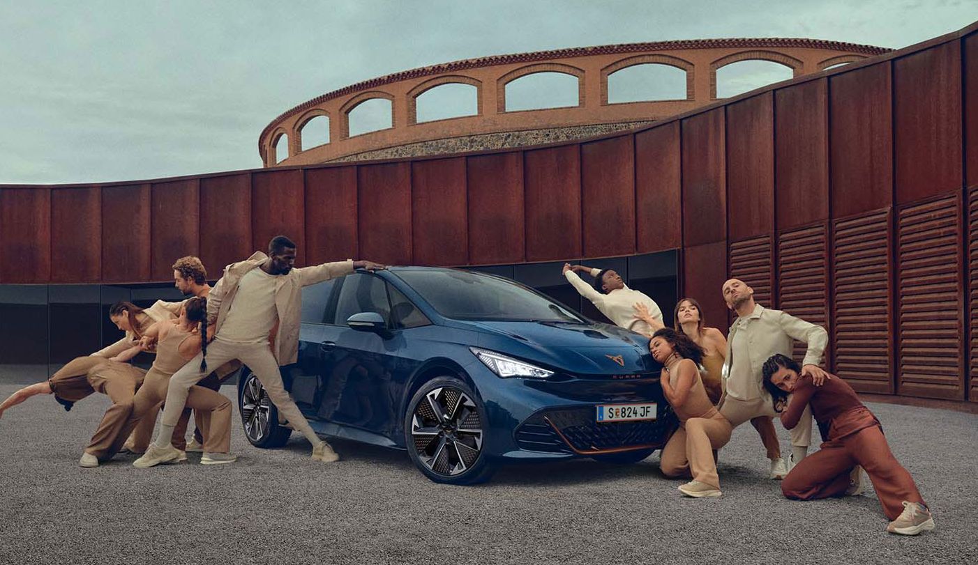 Ein blauer CUPRA Born steht auf einem Platz, mehrere Personen befinden sich links und rechts neben dem Fahrzeug.