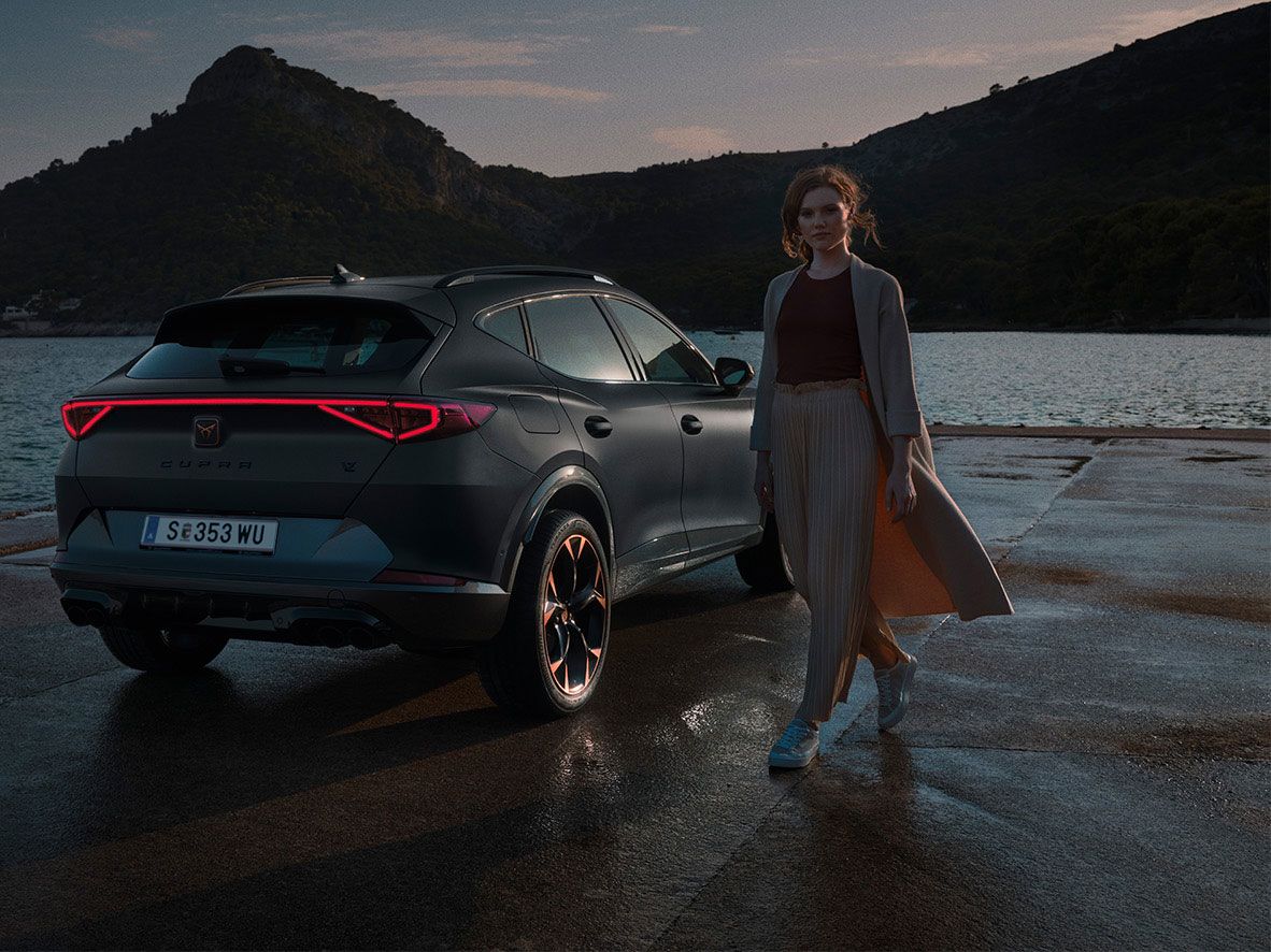CUPRA Formentor Heckansicht. Eine Frau steht neben dem Fahrzeug.