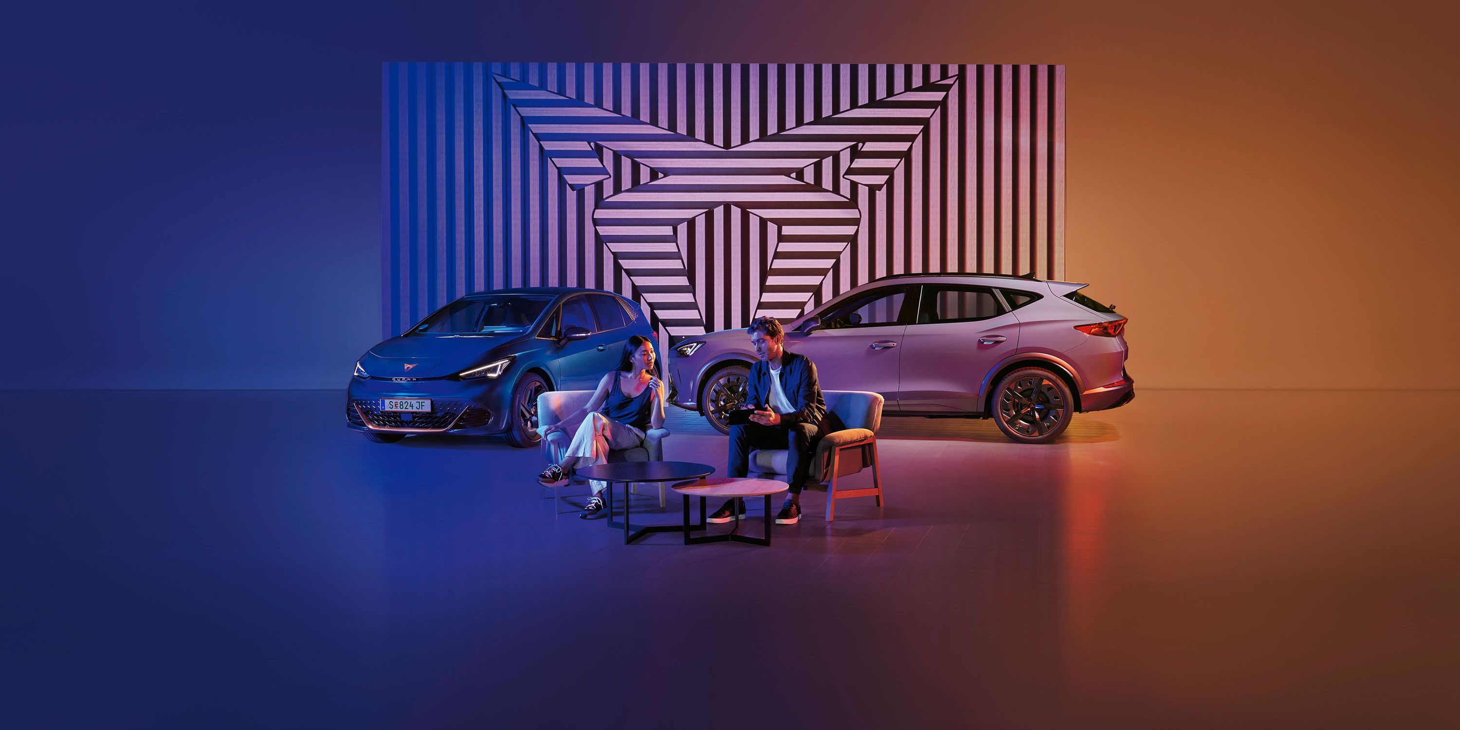 Zwei CUPRA Modelle-ein Mann und eine Frau sitzen davor