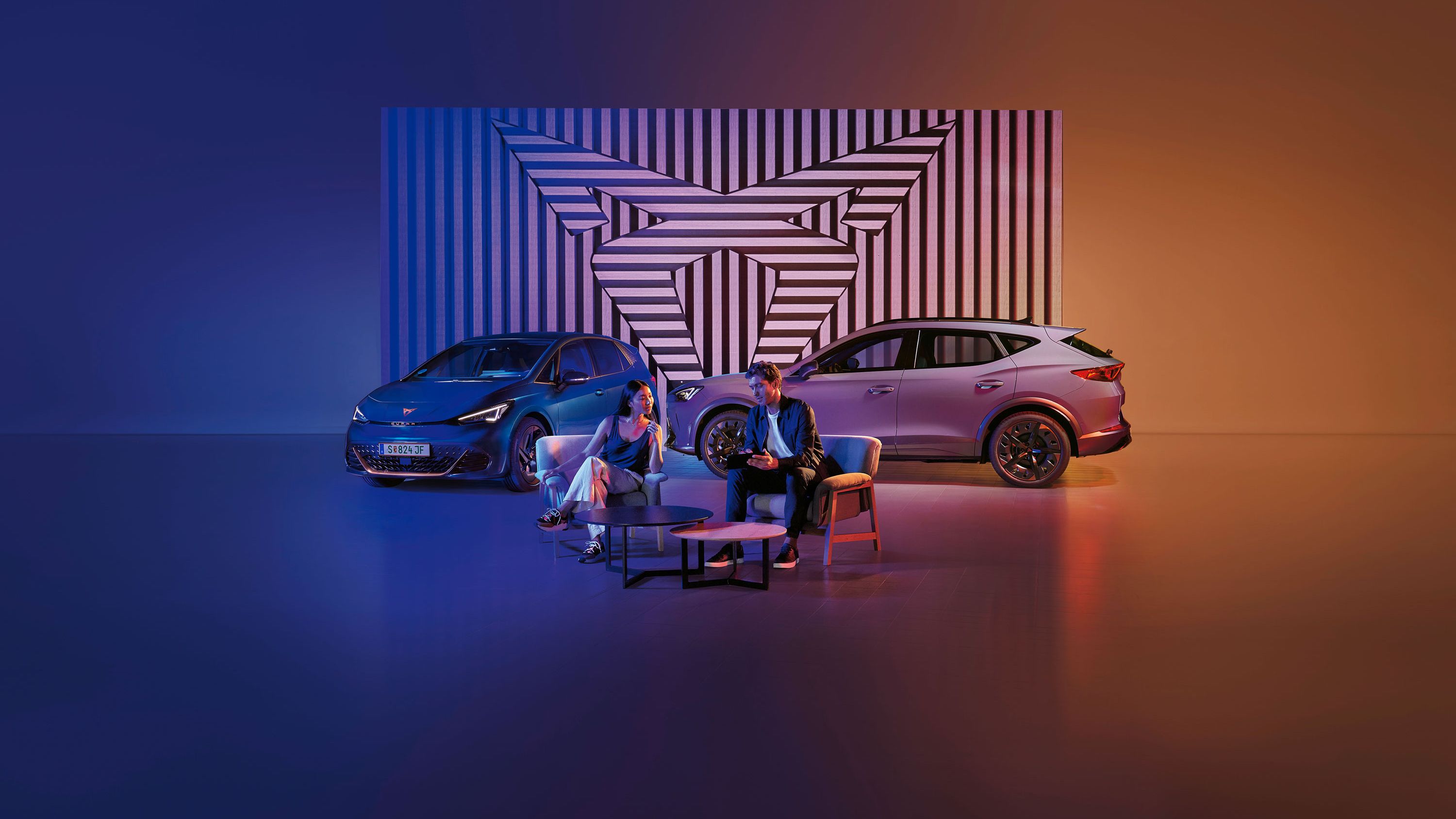 Zwei CUPRA Modelle-ein Mann und eine Frau sitzen davor