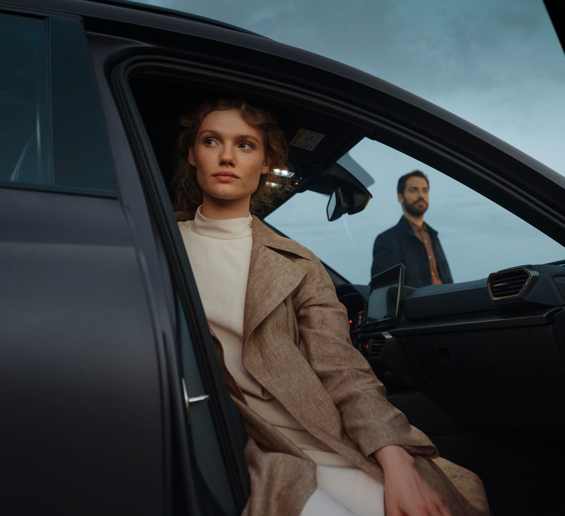 Eine Frau sitzt bei geöffneter Beifahrertür in einem CUPRA Formentor