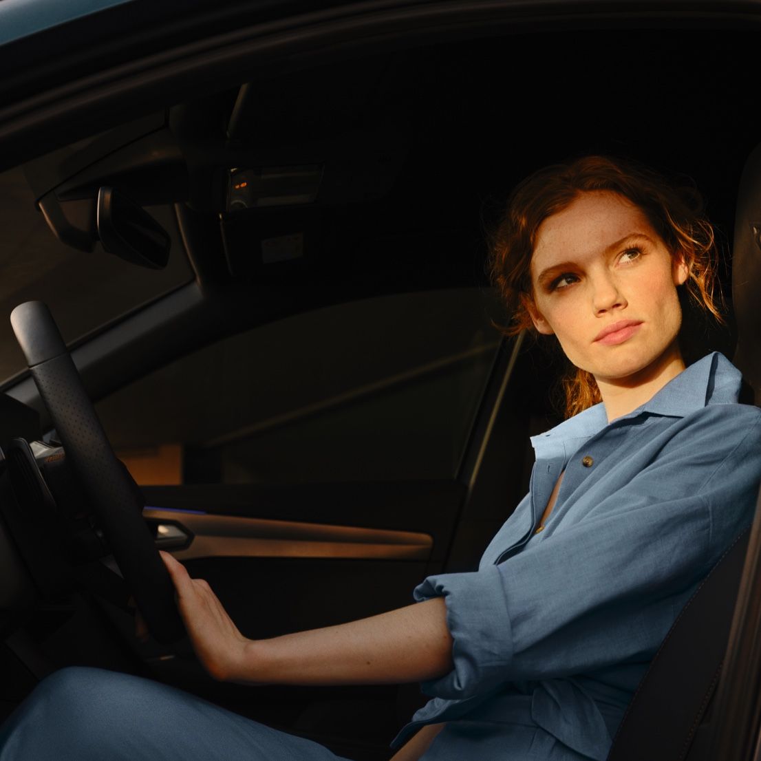 EIne Frau sitzt bei geöffneter Fahrertür am Steuer eines CUPRA Formentor