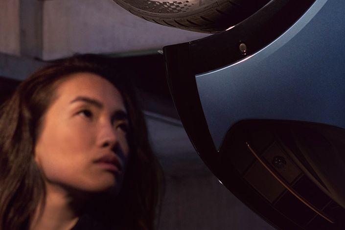 Detailansicht einer Felge des CUPRA Tavascan, eine Frau befindet sich neben dem Fahrzeug.