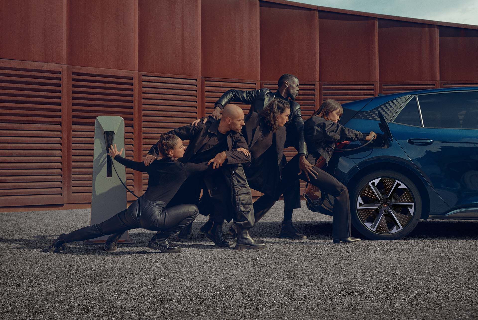 Eine Gruppe von Personen beim Aufladen eines blauen CUPRA Born an der Ladesäule.